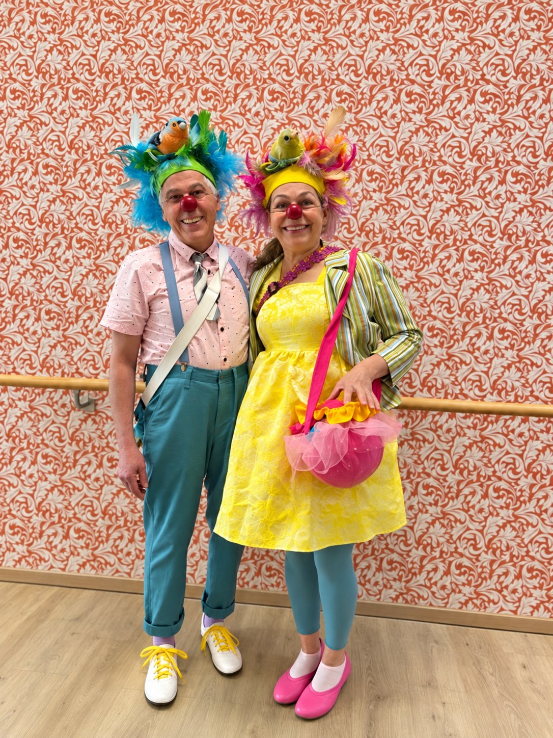 Das Clownduo trägt bunte gefiederte Vogelhüte und farbenfrohe Kostüme.